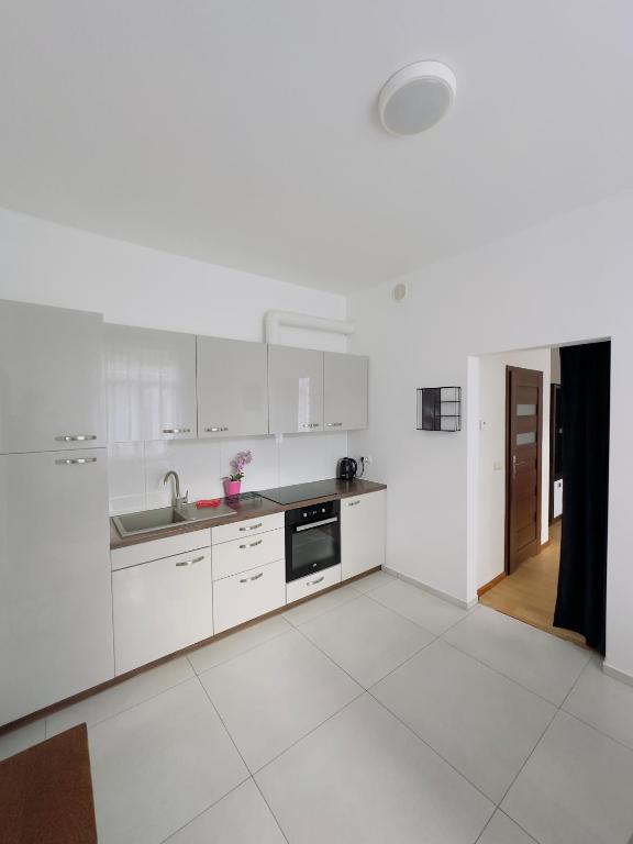 a white kitchen with a sink and a stove at Apartament Maja 10-3 in Nowy Sącz
