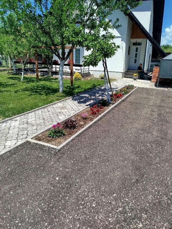 a driveway with a tree and flowers in a yard at Vila Zlaja in Bihać
