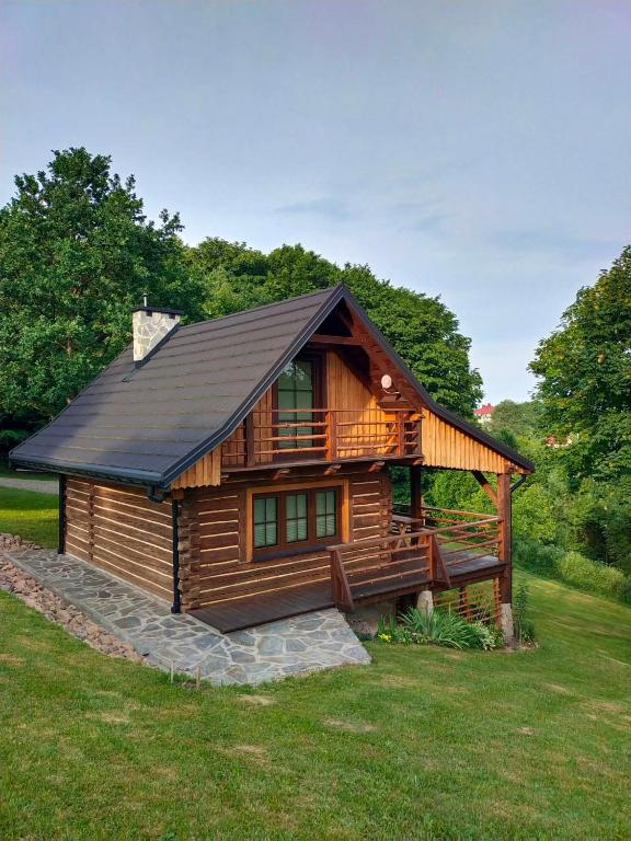 a log cabin with a black roof on a green field at Chatka Pod Dębem in Rozdziele