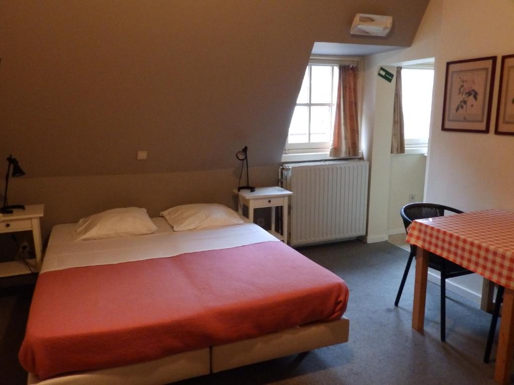 1 dormitorio con cama, mesa y ventana en Logies De Wandelaar, en Middelkerke