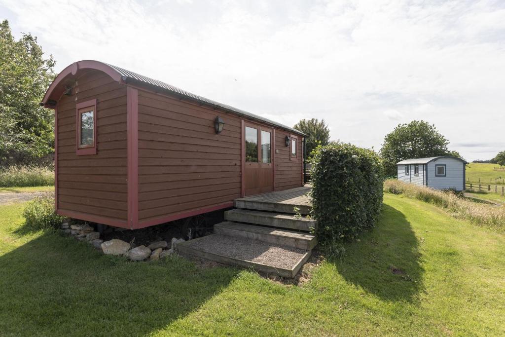 a tiny house with a staircase in a yard at Foxglove Shepherd's Hut in Berwick-Upon-Tweed