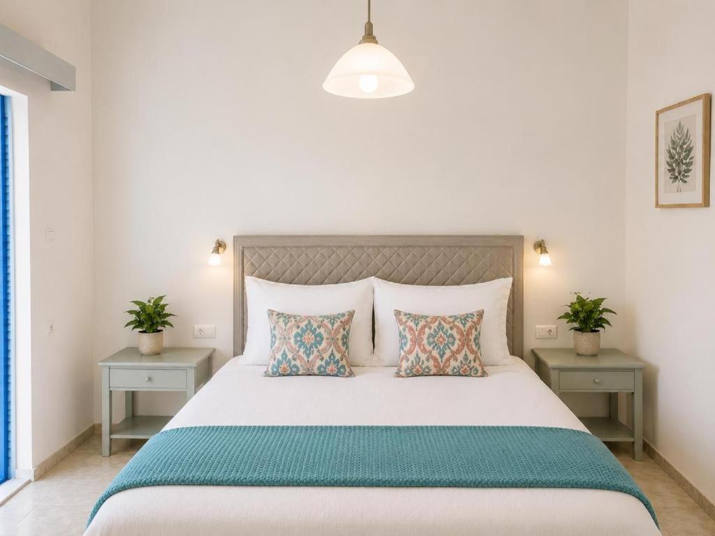 a bedroom with a large white bed with two tables at Klima Rooms in Palaiochora