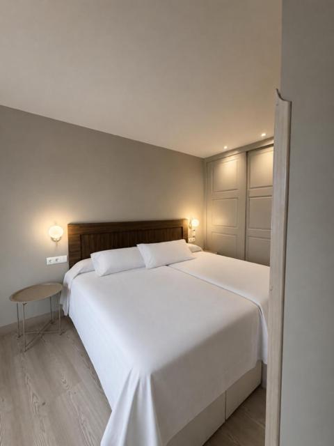 a large white bed in a room with a table at Escolapios Centro in Monforte de Lemos