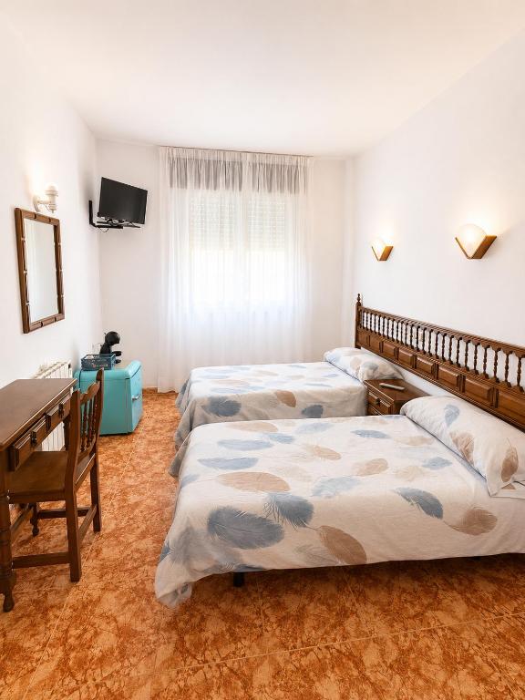 a room with two beds and a table and a desk at Soutullo Praia in Sanxenxo