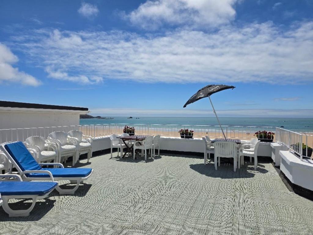 a patio with chairs and an umbrella on the beach at Beau Rivage in St. Brelade