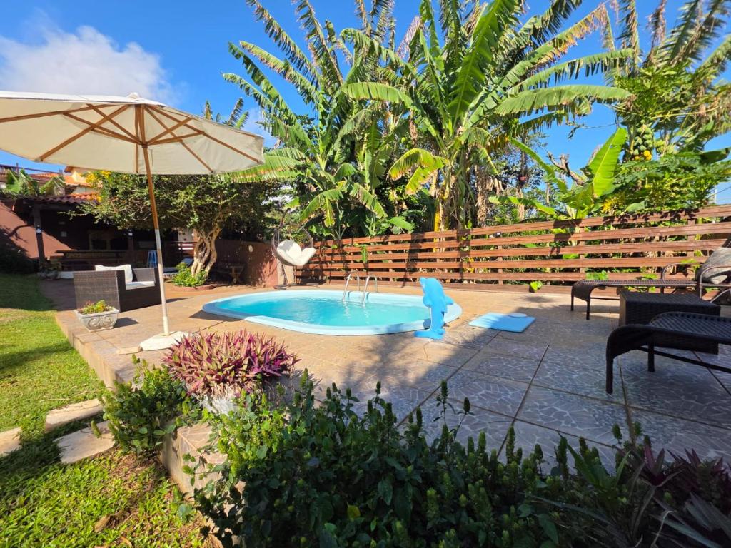 a pool in a yard with an umbrella at Namorada Brava Guest House Praia Brava, Piscina & Naturaleza in Búzios