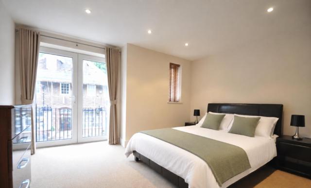 a bedroom with a large bed and a large window at Letting Serviced Apartments - Chorleywood Village in Chorleywood