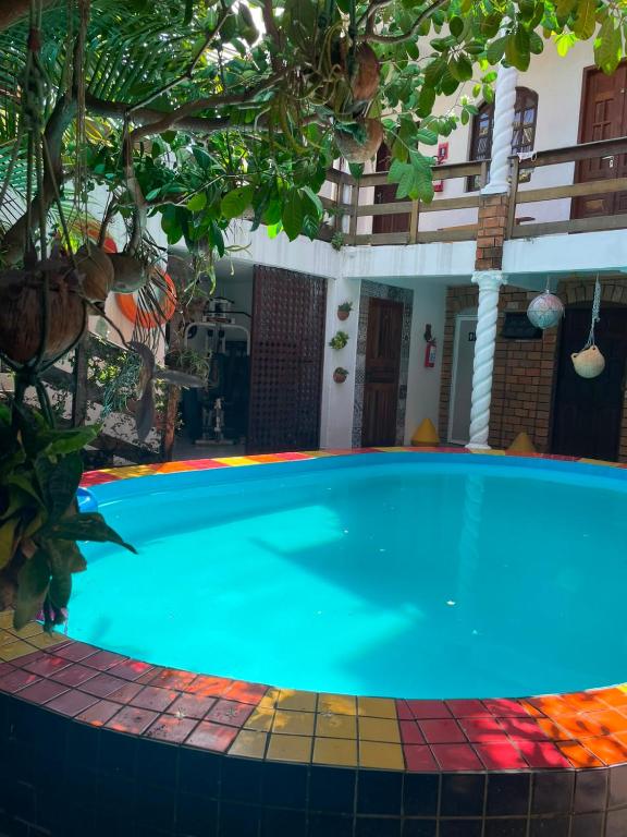 a large swimming pool in a yard with a tree at Recanto do caja in Porto De Galinhas