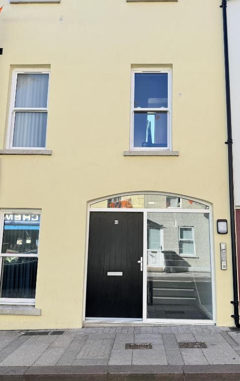 a building with a black door and two windows at Ogle Street 1-Bed Apartment in Armagh