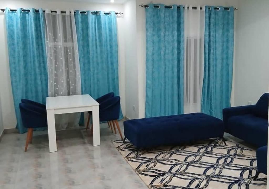 a living room with blue curtains and a table and chairs at Zahra Suites in Elephant Island