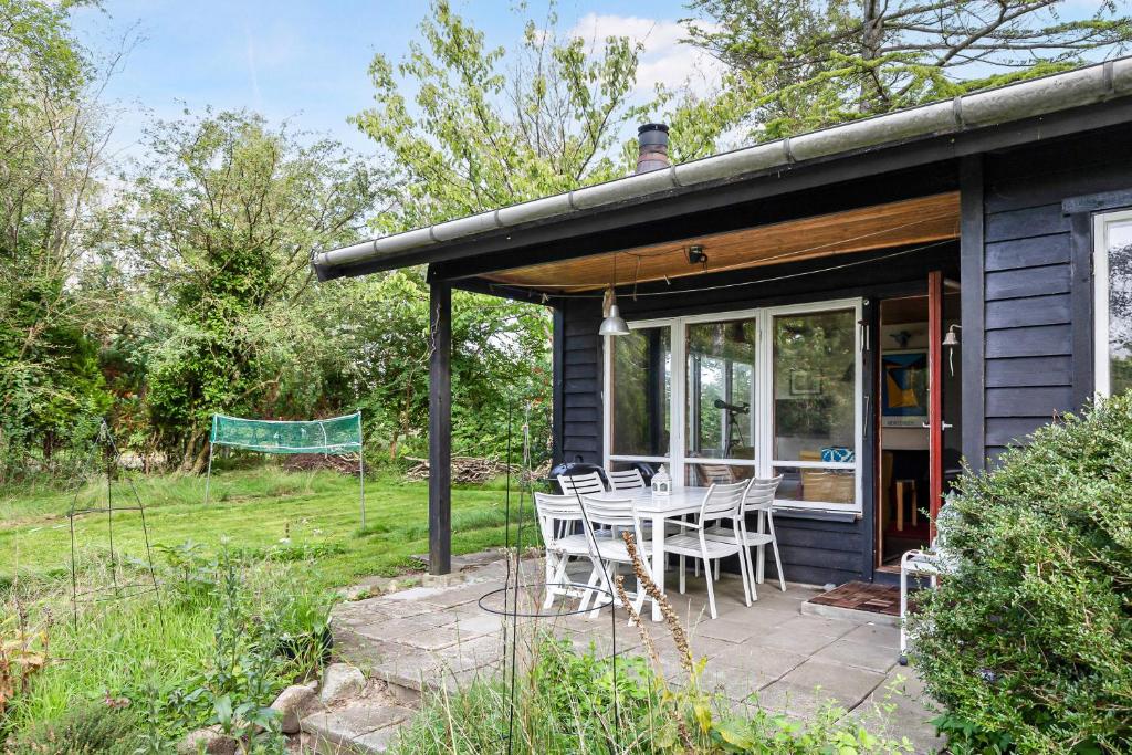 a house with a table and chairs on a patio at Cottage By Veddinge In Charming 70S Style in Fårevejle