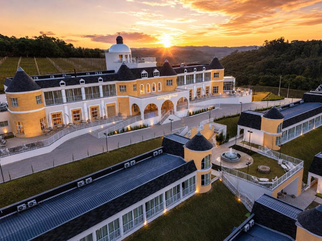 an aerial view of a mansion with the sunset in the background at Castelos do Vale by Livá OFICIAL in Bento Gonçalves
