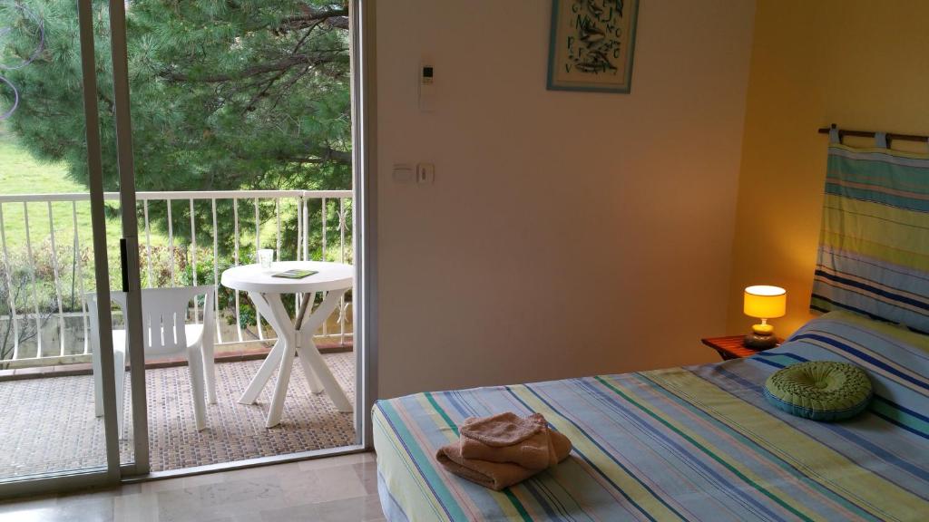 a bedroom with a bed and a balcony with a table at Chambres d&#39;hôtes et gîtes Al Pati in Sorède