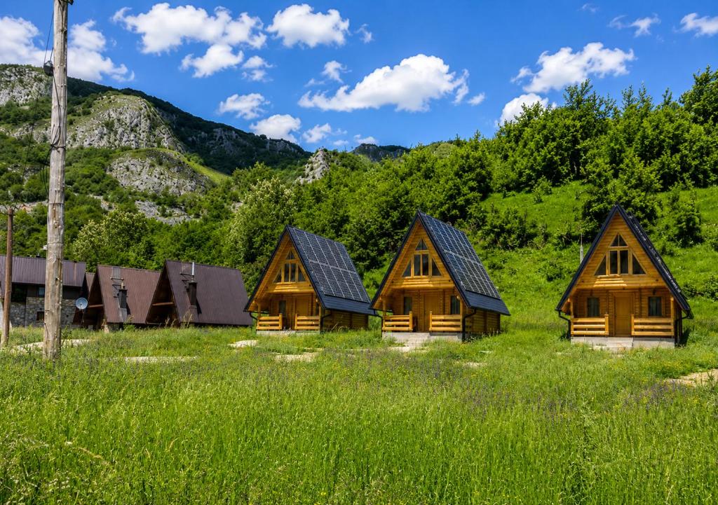 a group of wooden cabins in a field of grass at BB CHALET in Kolašin