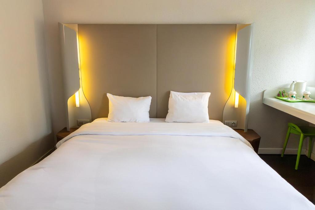 a large white bed with two pillows in a room at Campanile Grenoble Nord - Saint-Egrève in Saint-Égrève