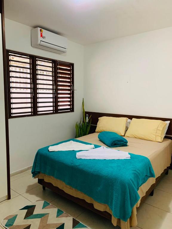 a bedroom with a bed with a blue blanket at Pousada e Hostel Praia do poço in Cabedelo