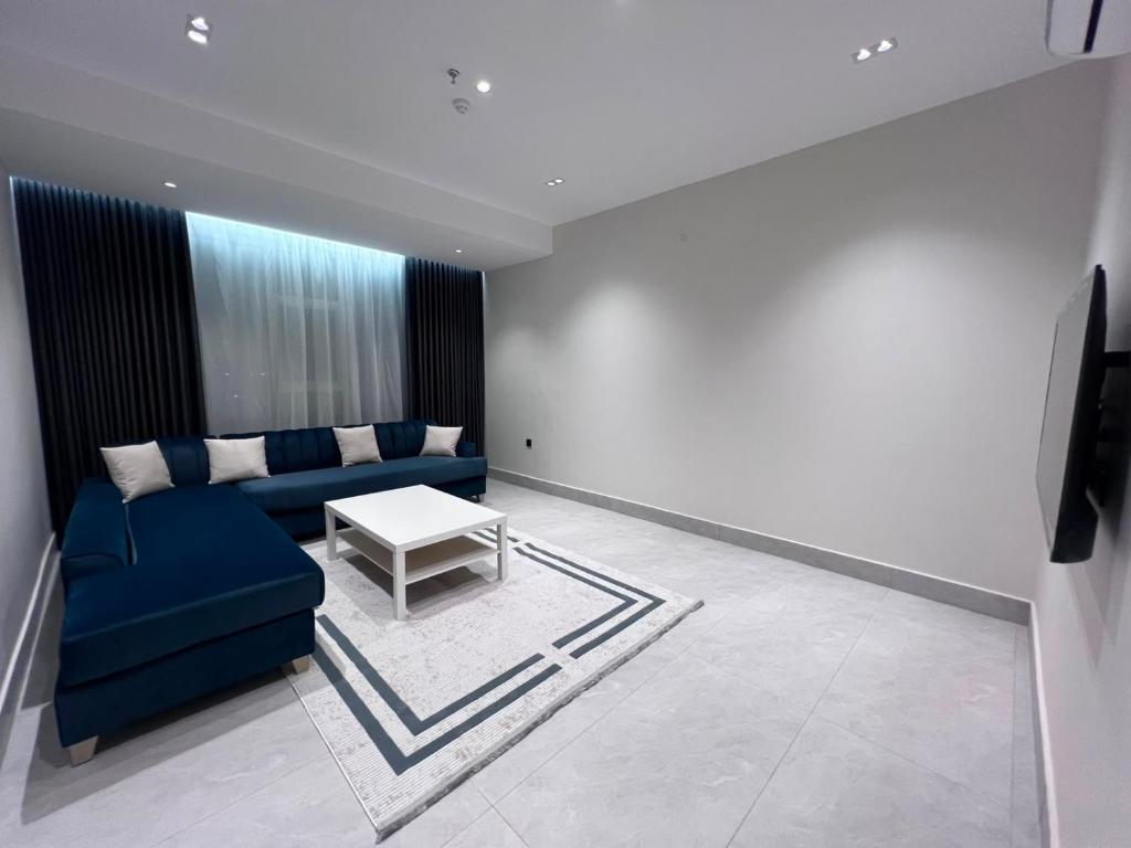 a living room with a blue couch and a table at البساتين بارك للشقق المخدومه in Al Baha