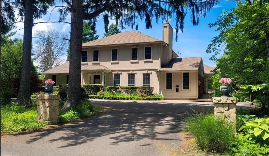 a large white house with trees and a driveway at Charlotte Garden Bed and Breakfast in Niagara-on-the-Lake