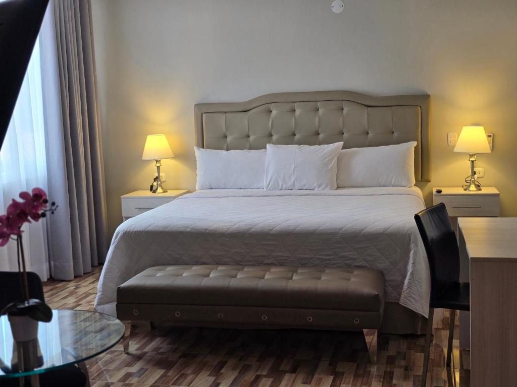 a bedroom with a bed and two lamps and a table at Terraza Apart Hotel in Pichanaki