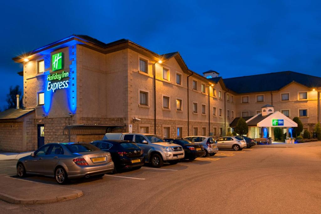 a row of cars parked in a parking lot in front of a hotel at Holiday Inn Express Inverness by IHG in Inverness