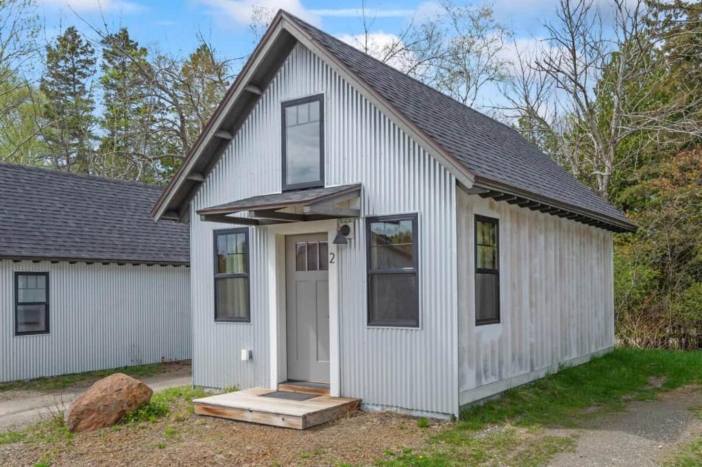 a white house with a white door and windows at The Lupine | Cross Stone Cabins • Walk to Rangeley Lake in Rangeley
