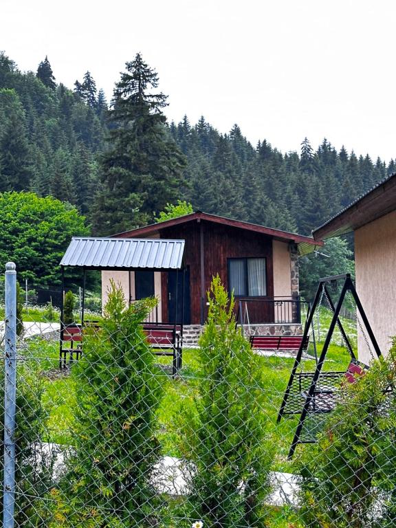 a fence in front of a house with a building at "Mtis broli 77"-Mzetamze-Borjomi in Mzet'amze