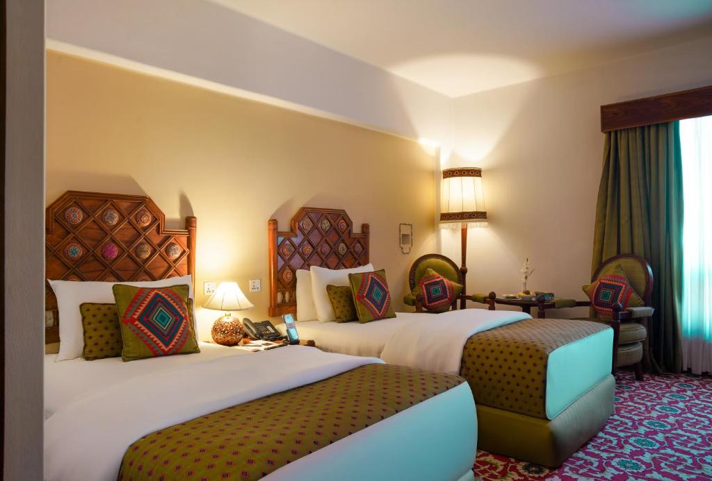 a hotel room with two beds and a living room at Quetta Serena Hotel in Quetta