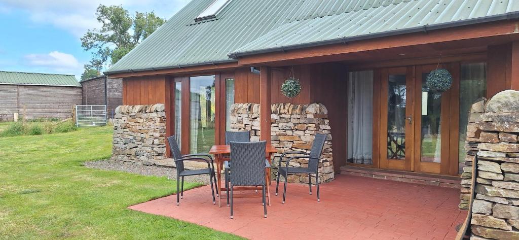 a patio with a table and chairs and a stone wall at Tarnside Cottages in Brampton