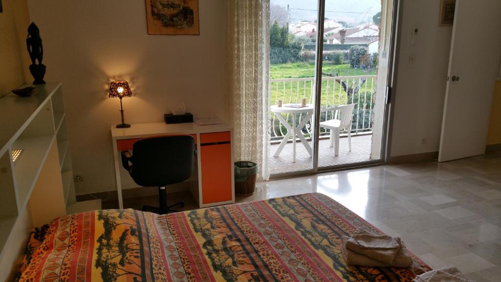 a bedroom with a bed and a desk and a balcony at Chambres d&#39;hôtes et gîtes Al Pati in Sorède