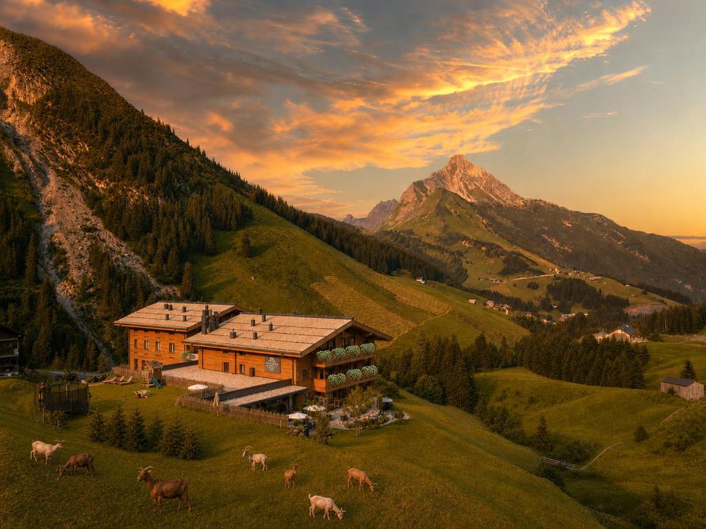 a house on a hill with cows in a field at LUX ALP CHALET am Arlberg in Warth am Arlberg