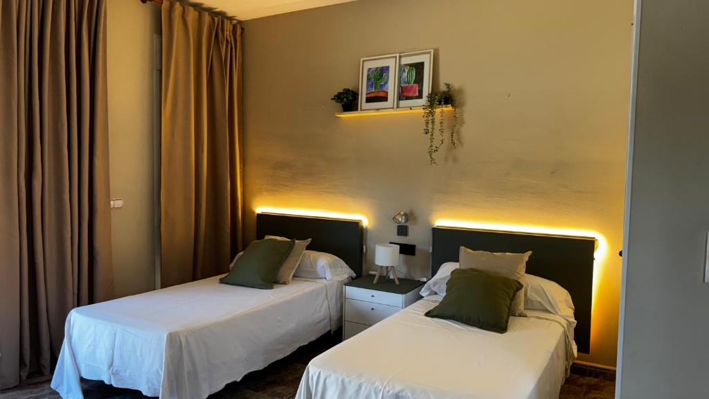 two beds in a room with white sheets and green pillows at Hotel Restaurant Europeu in Montmeló