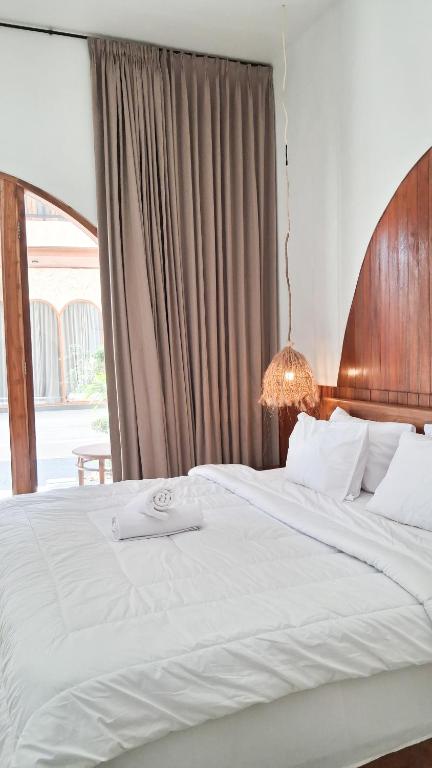 a bedroom with a large white bed with a window at Heritage Stay in Bingin Beach