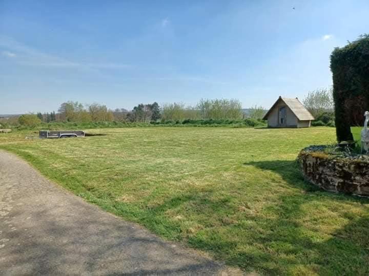 a field of grass with a house in the background at Emplacement camping car terrain privé cher l'habitant à Plœuc-L'Hermitage in Pourhon