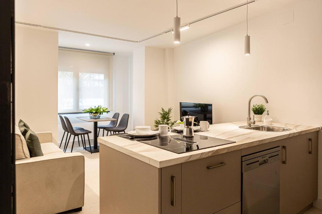 a kitchen and a living room with a table at Royar Apartamentos in Jaén