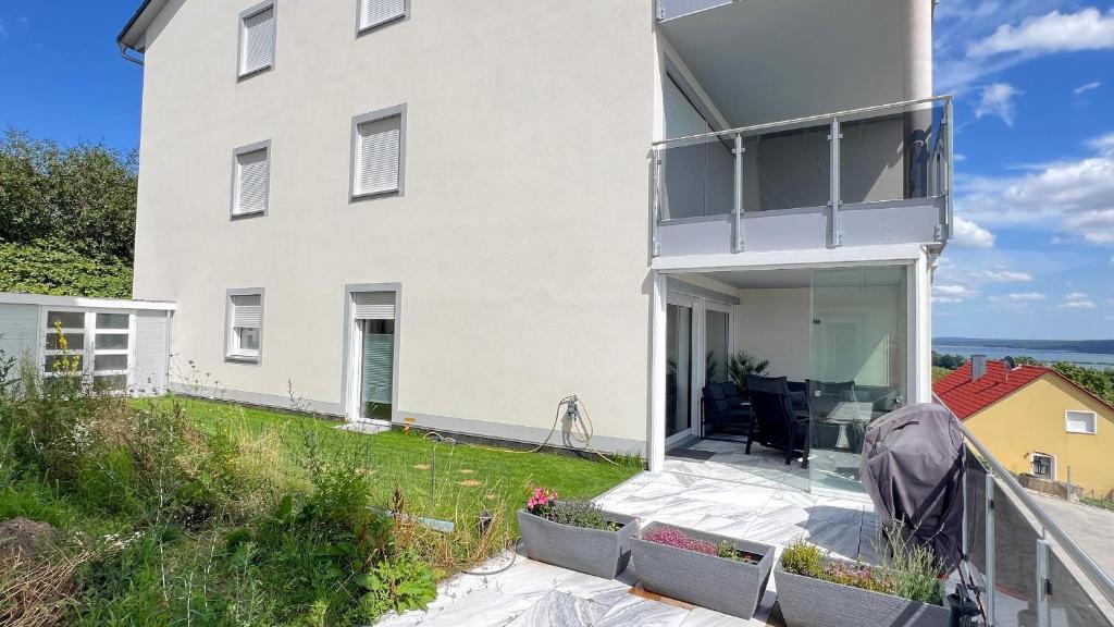 a white house with a patio and a balcony at FeWo-Brombachseeblick in Absberg