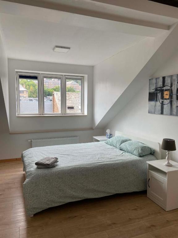 a bedroom with a large bed and two windows at Hébergement Citabelle in Dinant