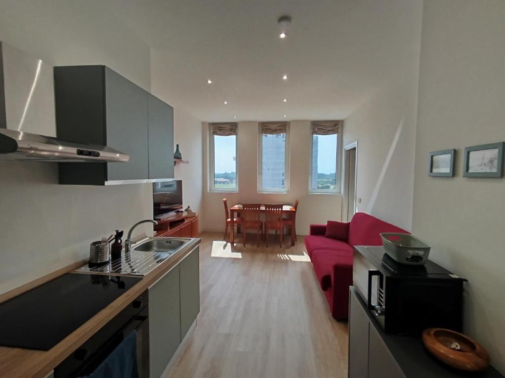 a kitchen and a living room with a red couch at Patecchio2-IEO Fondazione Prada Villaggio Olimpico in Vigentino