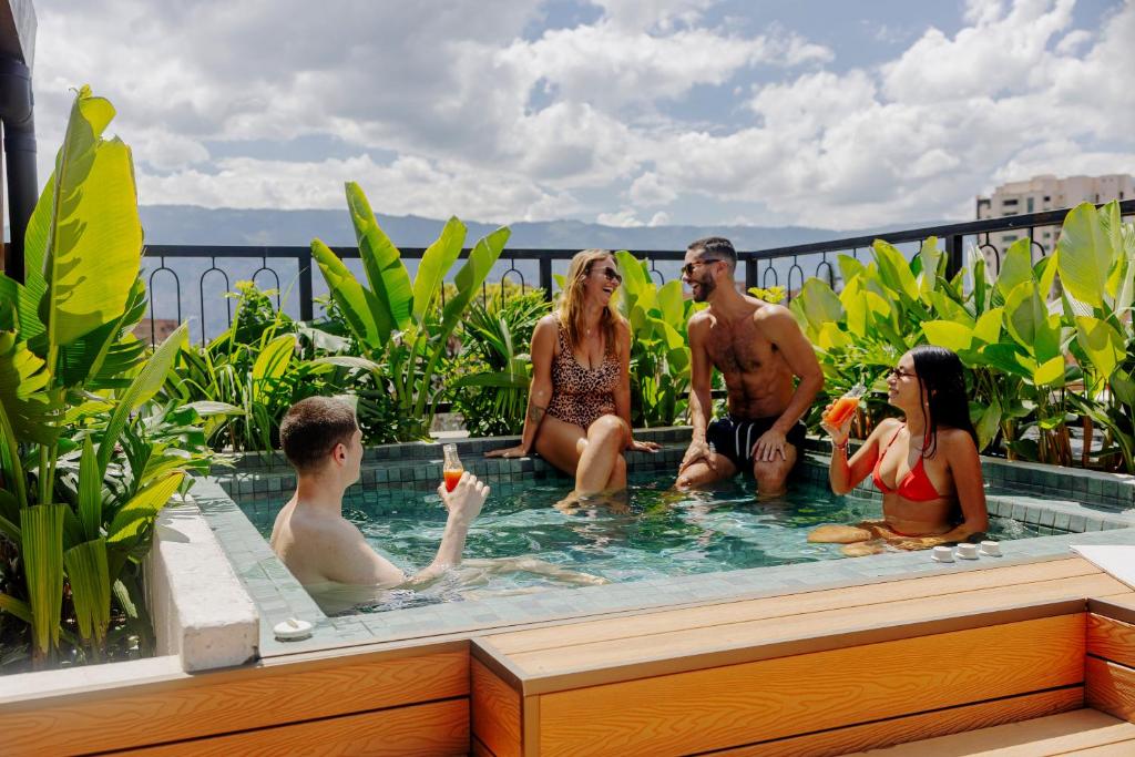 a group of people sitting in a swimming pool at Pranik Living Wellness Coliving Laureles Medellin in Medellín