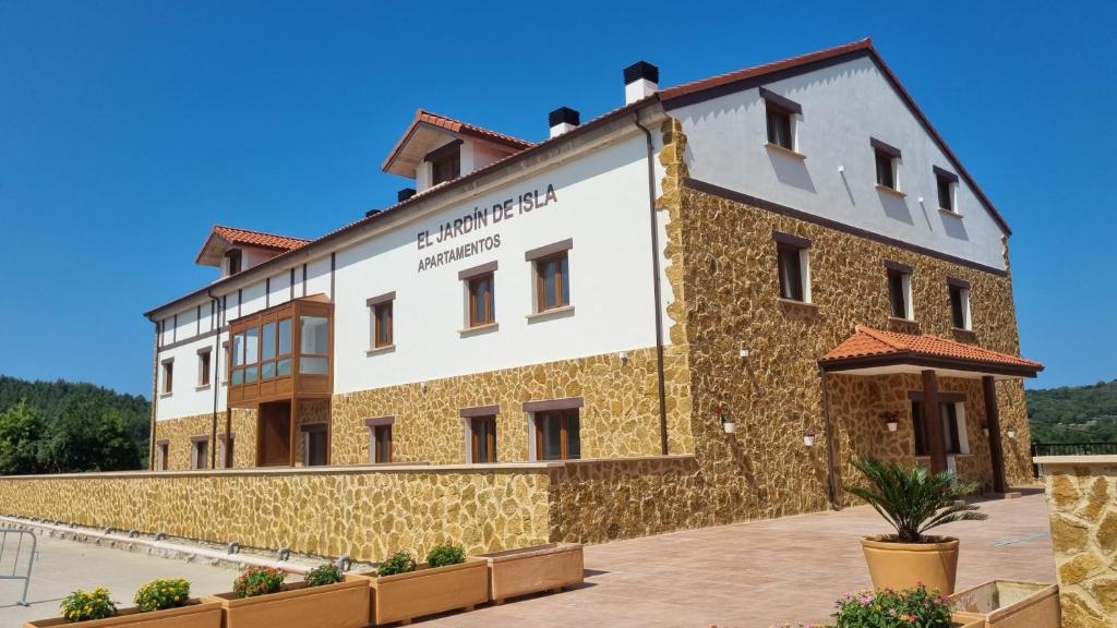 a large building with a stone facade at Apartamentos El Jardín de Isla Autocheck-In in Isla