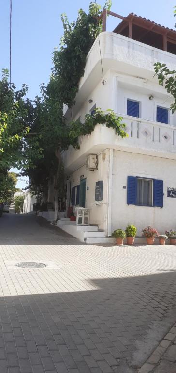 a white building with blue shutters on it at Angelos Rooms in Myrtos