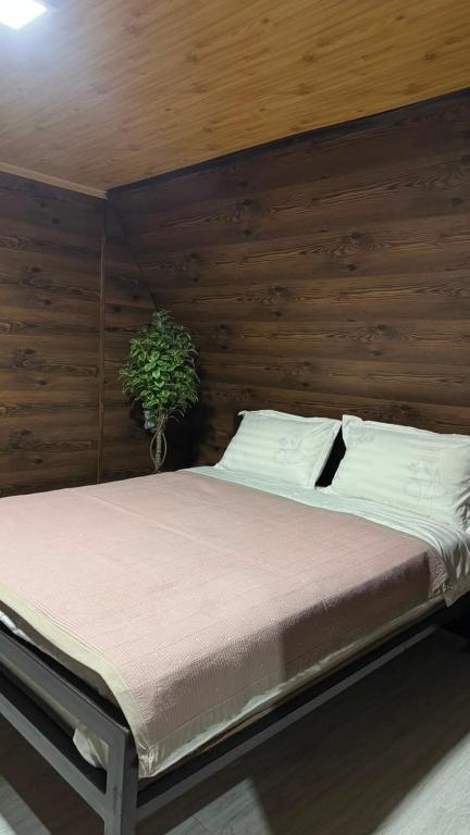 a bed in a room with a wooden wall at Baet Home in Bayetovka