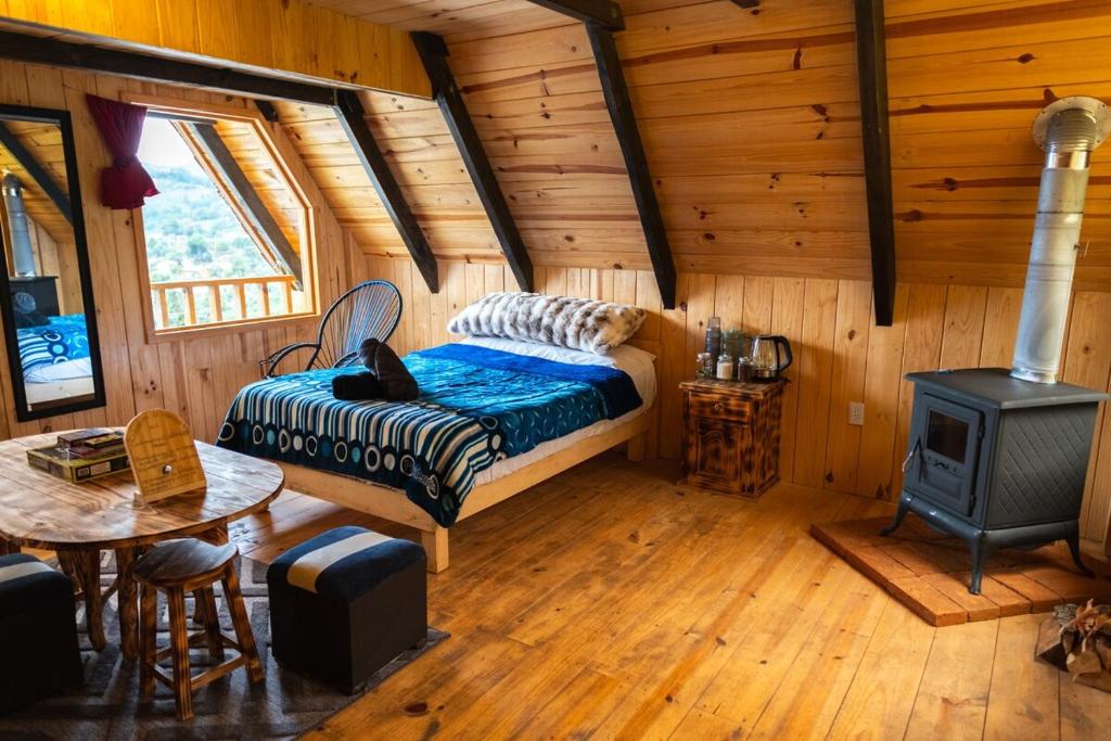 a bedroom with a bed and a stove in a cabin at El Paraje Cabaña 2 in San Andrés Paxtlán