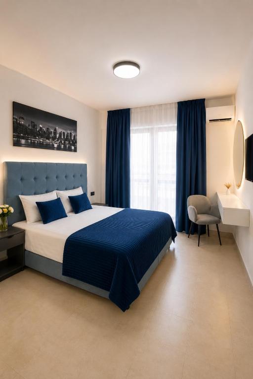 a bedroom with a large bed with blue sheets and a chair at Hotel Tommy in Budva