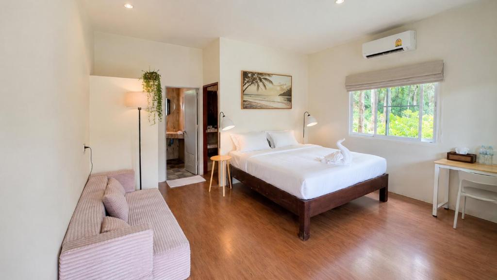 a bedroom with a bed and a couch and a window at Zen Village in Ko Phangan