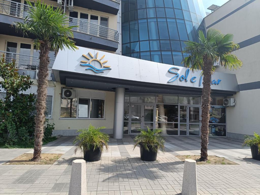 a building with palm trees in front of it at Sol e Mar in Sunny Beach