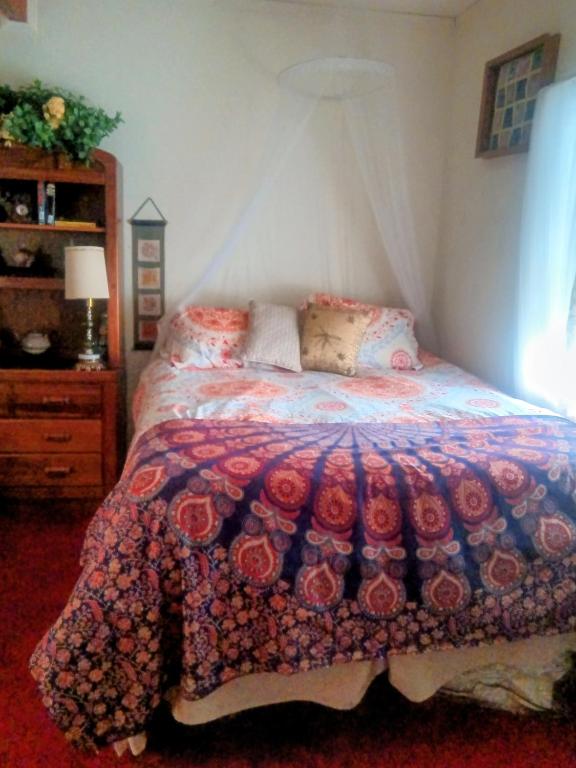 a bedroom with a bed with a colorful comforter at WELCOME TO My COTTAGE in Sunland