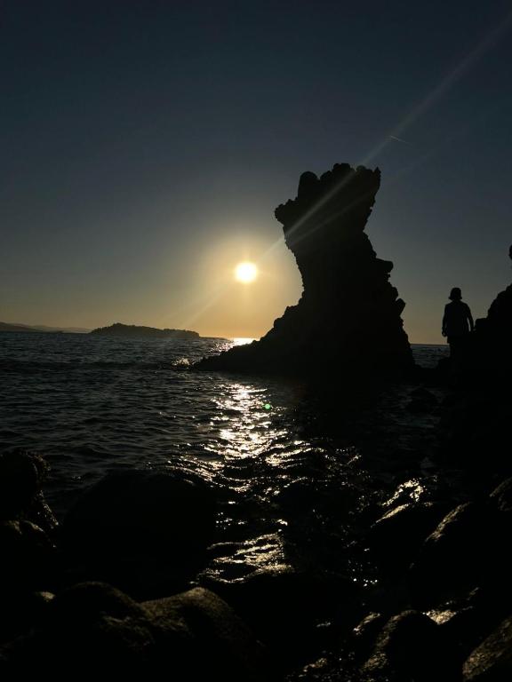 a person standing on the beach watching the sunset at Agape’s apartment in Anaxos