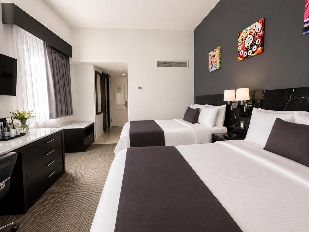 A two-bed room with a work surface, beverage station, window and dark feature wall.