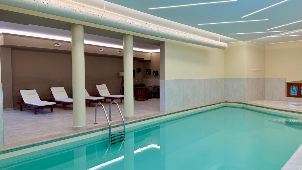 ein Pool in einem Hotelzimmer mit Stühlen und Tischen in der Unterkunft HC Hotel Cremona Pilgrim's in Cicognolo