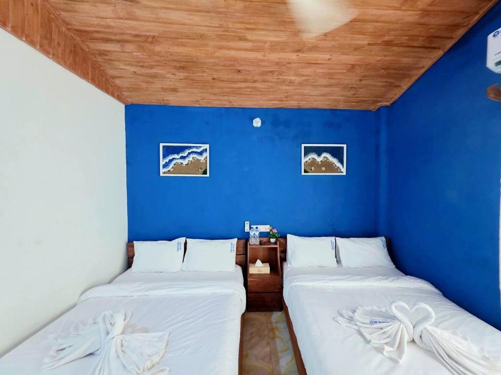 two beds in a room with a blue wall at Coastal daisy Beach resort in Cox's Bazar